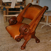 Custom upholstered armchair in tobacco leather with carved walnut frame
